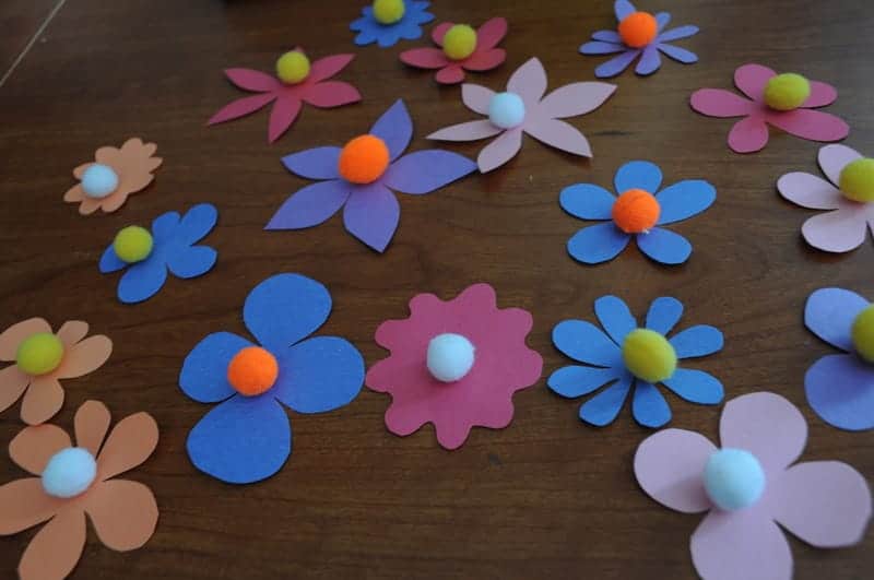 Add pom poms in the center of the flower cutouts